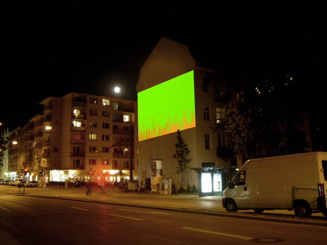 Fotografie der Großprojektion "Bunter Abend" von Wolfgang Aichner und Thomas Huber an einer Gebäudefassade in der Müllerstr. 10 bei Nacht. In der Projektion fließen vom oberen Rand des Projektionsausschnittes zwei Töne zähflüssiger Malfarbe – grün und rot – übereinander.