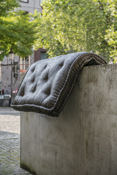 Image of a fountain sculpture by Tatiana Trouvé on Stephansplatz. The sculpture consists of a cast of a mattress placed over a concrete base.