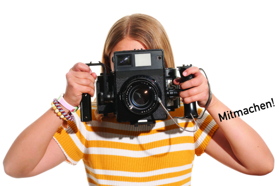 A young girl in front of a white background holds a camera in front of her eyes