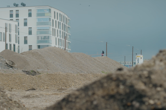 Das Bild zeigt die Baustelle mit Erdaushub und bereits fertige Wohnblocks