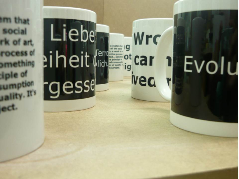 The photograph shows a series of cups in black and white with different words and texts printed on them.