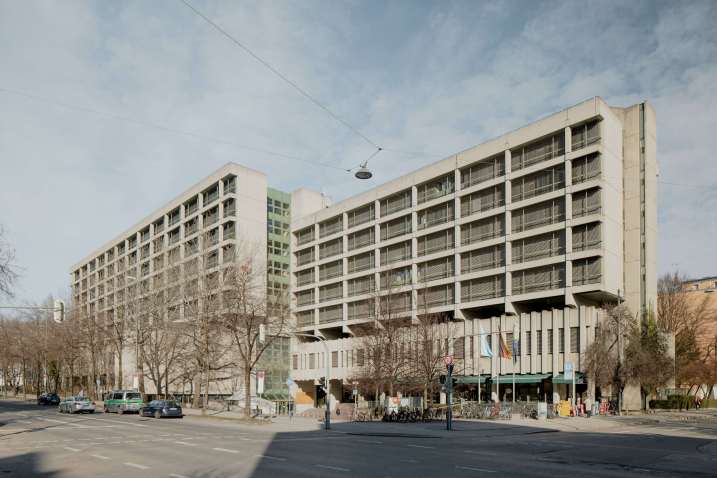 Photograph of the criminal justice centre on Nymphenburger Straße. You can see the grey exposed concrete building from the 1970s and the road junction in front of the building.