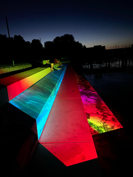 Young people sit on illuminated steps outside at night