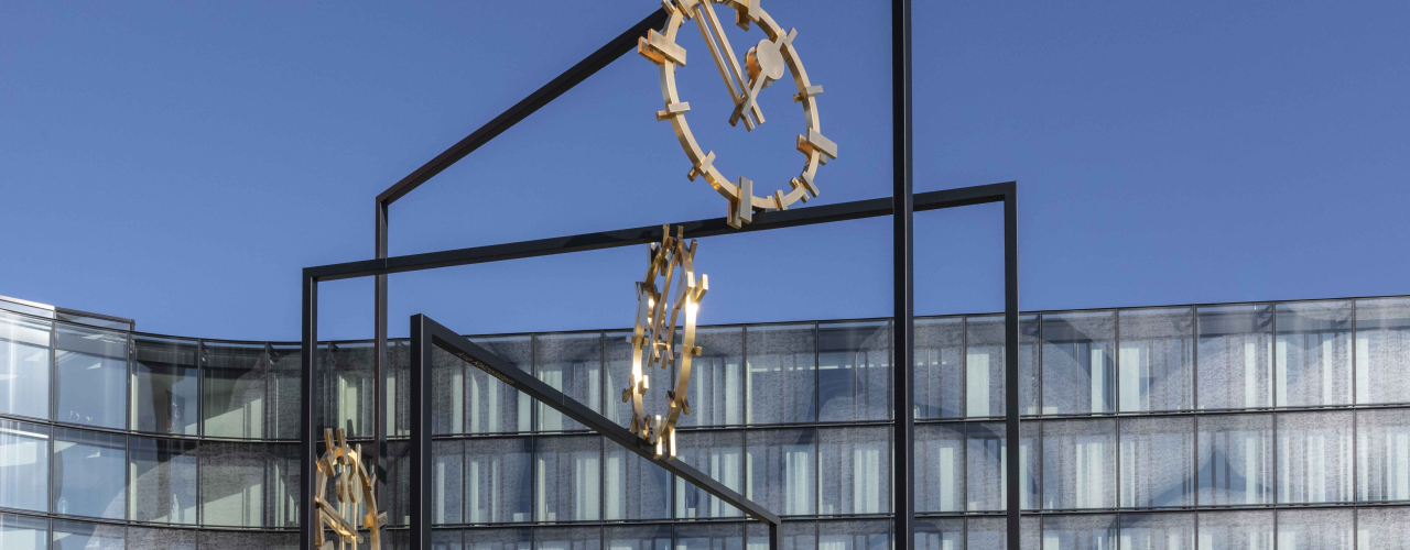 Eine große Skulptur aus Stahl mit drei goldenen Ziffernblättern