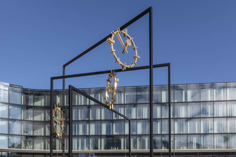 Eine große Skulptur aus Stahl mit drei goldenen Ziffernblättern