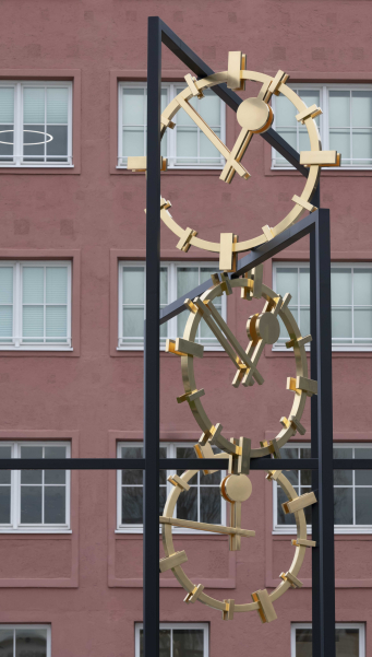 Eine große Skulptur aus Stahl mit drei goldenen Ziffernblättern