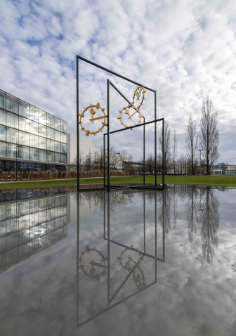 Eine große Skulptur aus Stahl mit drei goldenen Ziffernblättern